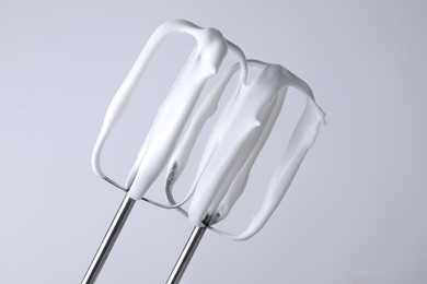 Photo of Whisks with whipped cream on white background, closeup