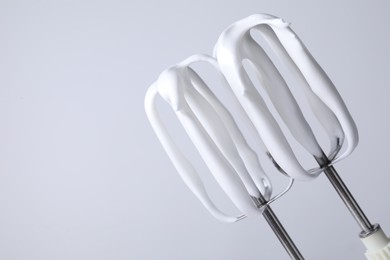 Photo of Whisks with whipped cream on white background, closeup. Space for text