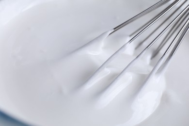 Photo of Whisk and whipped cream in bowl, closeup