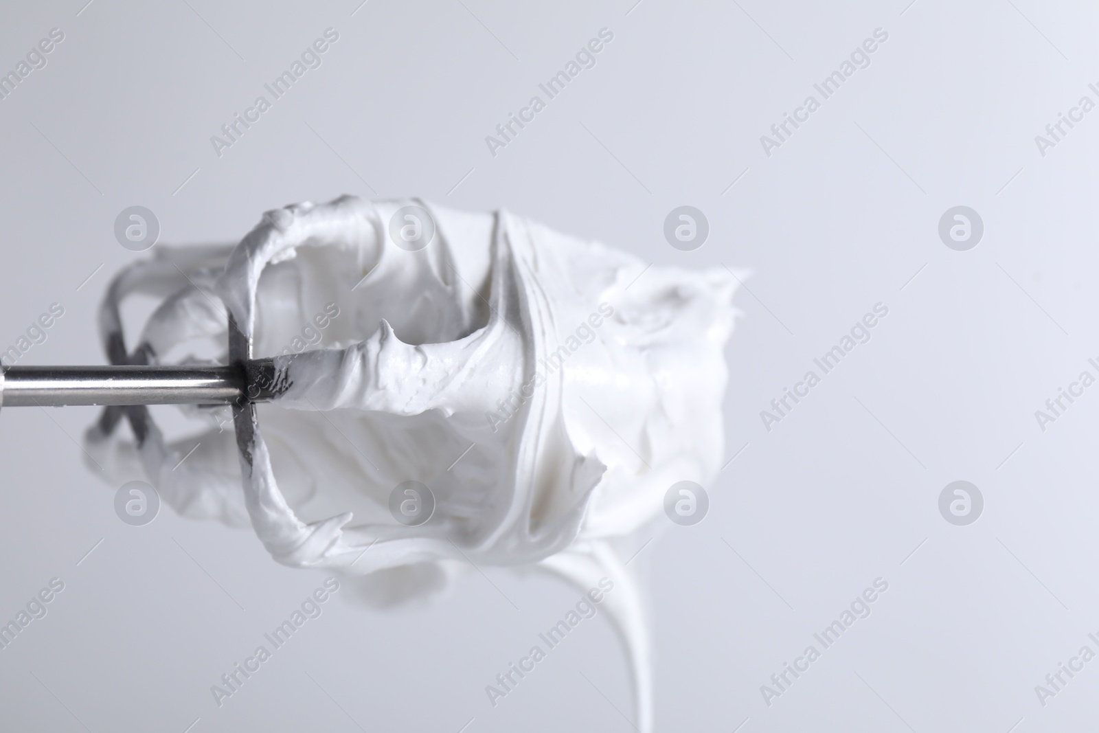 Photo of Whisks with whipped cream on white background, closeup. Space for text