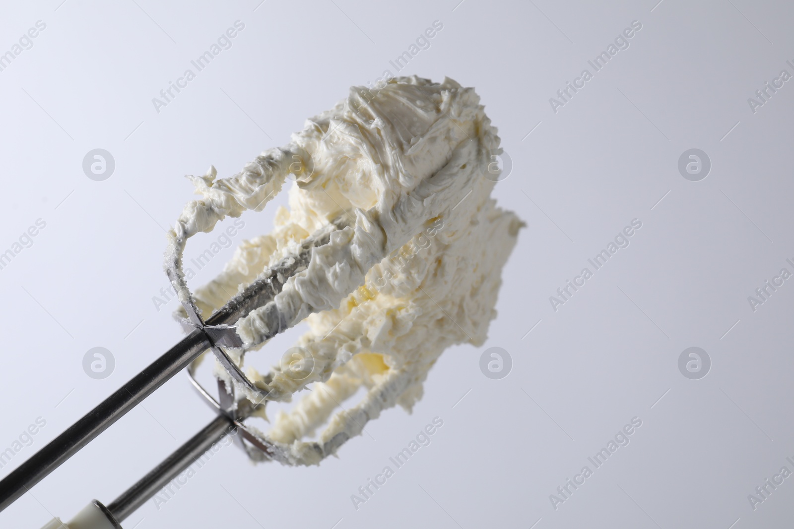 Photo of Whisks with whipped cream on white background, closeup. Space for text