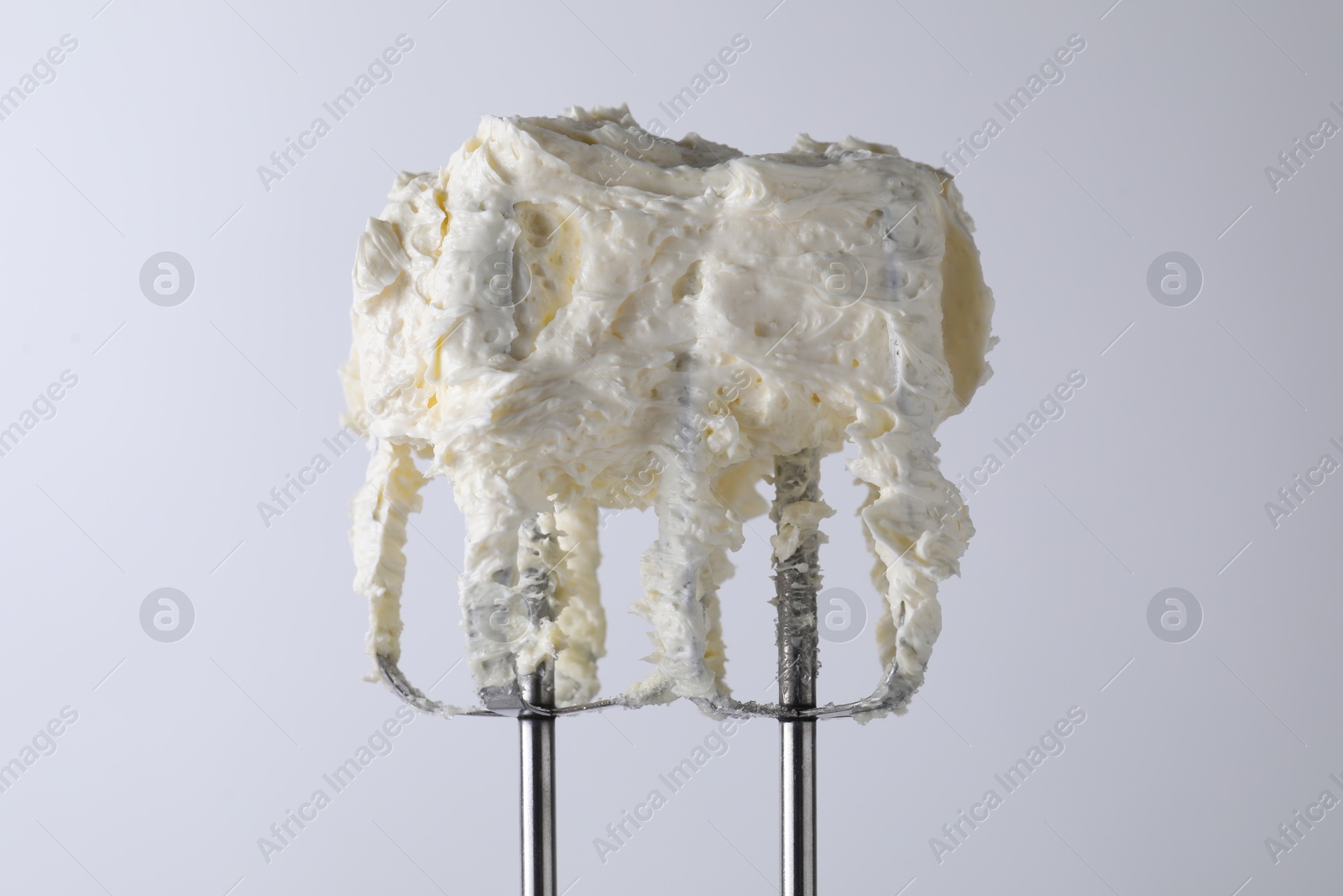 Photo of Whisks with whipped cream on white background, closeup