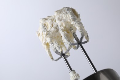 Photo of Whisks with whipped cream on white background, closeup