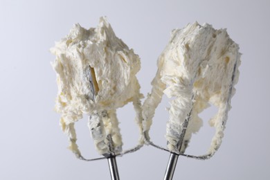 Photo of Whisks with whipped cream on white background, closeup