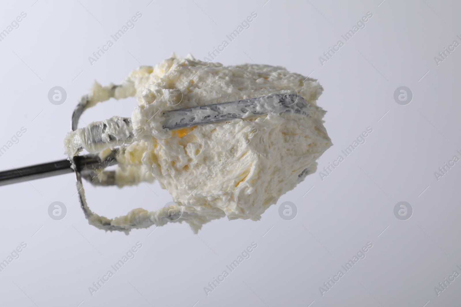 Photo of Whisk with whipped cream on white background, closeup