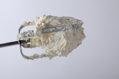 Photo of Whisk with whipped cream on white background, closeup