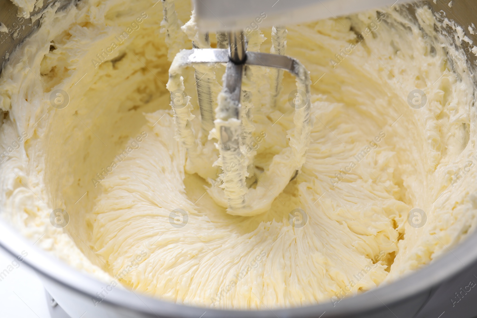 Photo of Mixing whipped cream in bowl with stand mixer, closeup