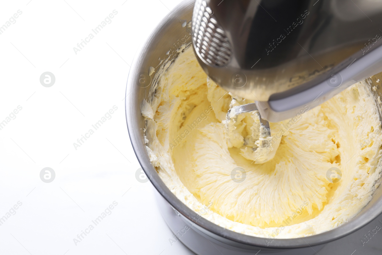 Photo of Mixing whipped cream in bowl with stand mixer on white table, closeup. Space for text