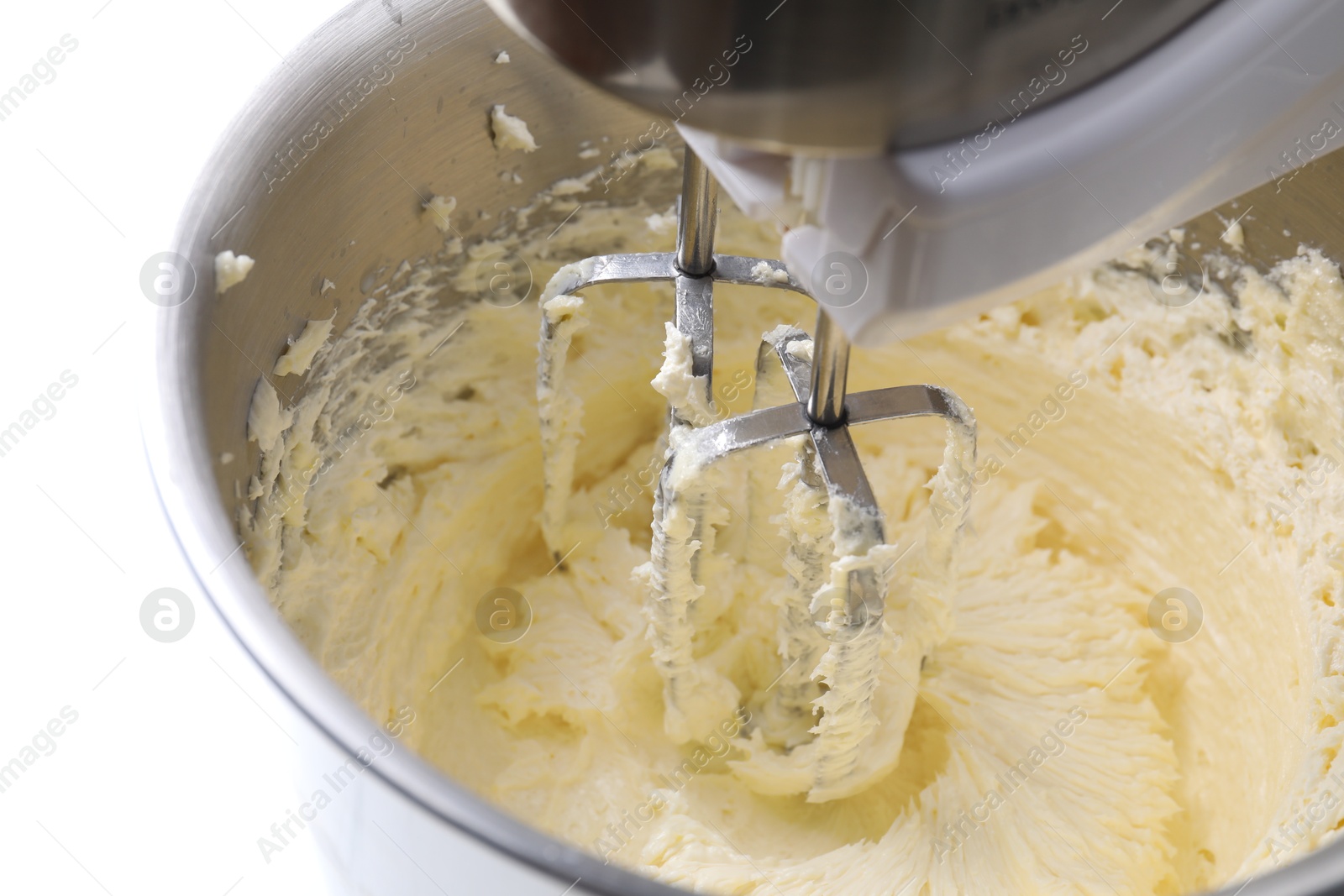 Photo of Mixing whipped cream in bowl with stand mixer on white table, closeup