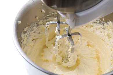 Photo of Mixing whipped cream in bowl with stand mixer on white table, closeup