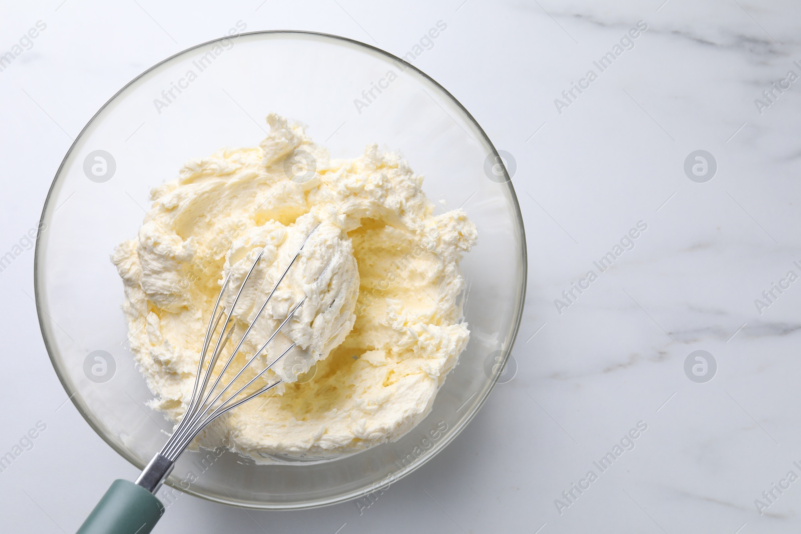 Photo of Bowl with whisk and whipped cream on white marble table, top view. Space for text