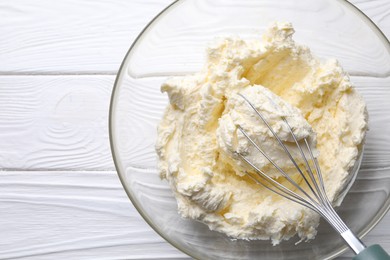 Photo of Bowl with whisk and whipped cream on white wooden table, top view. Space for text