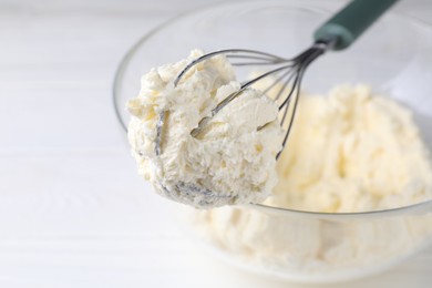 Photo of Bowl with whisk and whipped cream on white table, closeup