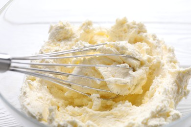 Photo of Bowl with whisk and whipped cream on white table, closeup