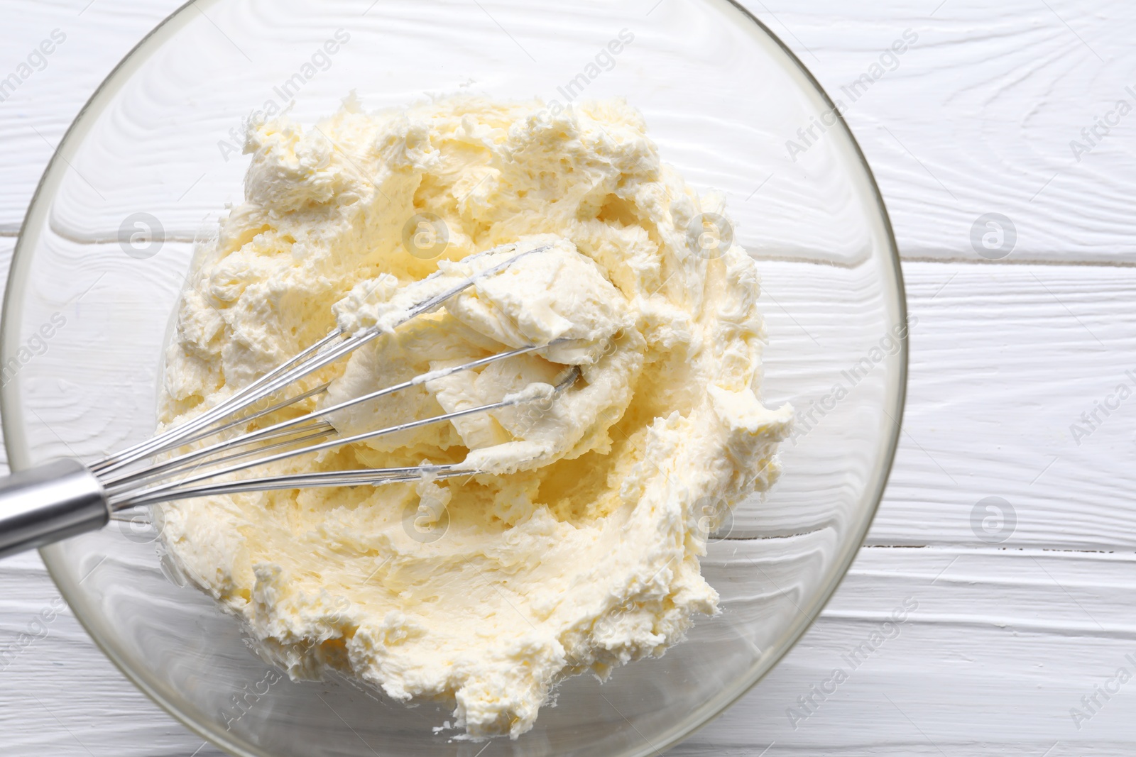 Photo of Bowl with whisk and whipped cream on white wooden table, top view