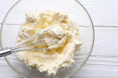 Photo of Bowl with whisk and whipped cream on white wooden table, top view