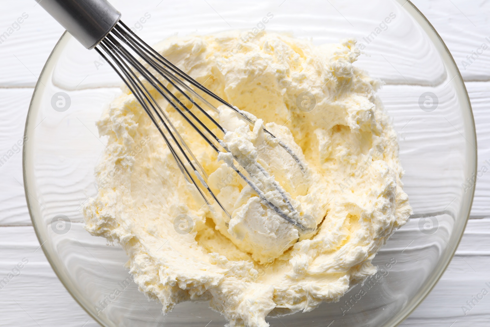 Photo of Bowl with whisk and whipped cream on white wooden table, top view