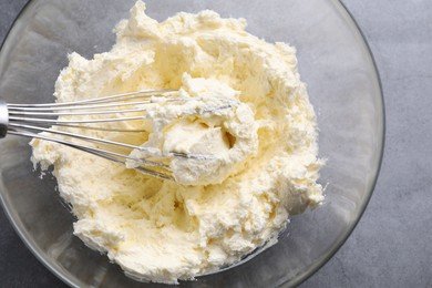 Photo of Bowl with whisk and whipped cream on grey table, top view