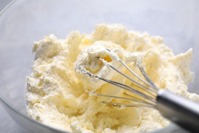 Photo of Bowl with whisk and whipped cream on grey table, closeup