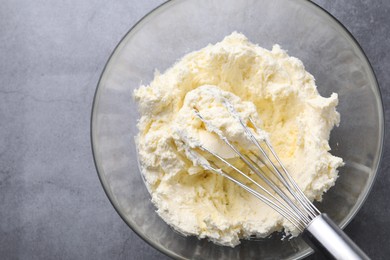 Photo of Bowl with whisk and whipped cream on grey table, top view