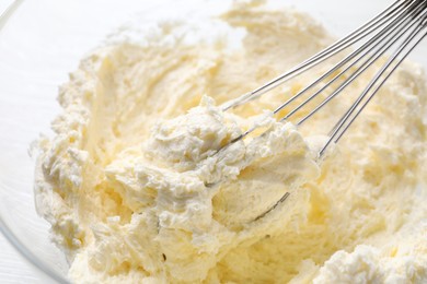 Photo of Bowl with whisk and whipped cream on table, closeup