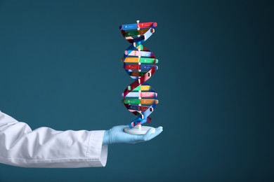 Photo of Scientist holding DNA structure model on dark blue background, closeup