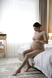 Photo of Beautiful pregnant woman on bed at home. Space for text