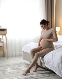 Photo of Beautiful pregnant woman on bed at home. Space for text