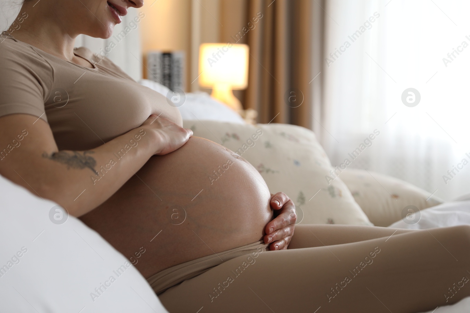 Photo of Beautiful pregnant woman on bed at home, closeup. Space for text