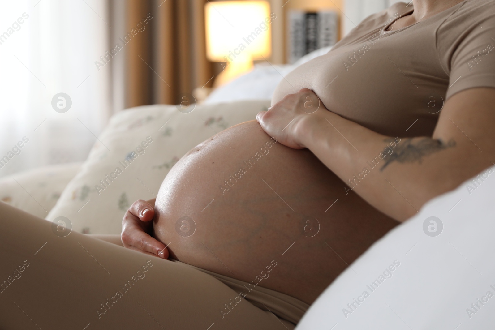 Photo of Beautiful pregnant woman on bed at home, closeup. Space for text