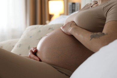 Beautiful pregnant woman on bed at home, closeup. Space for text