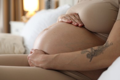 Pregnant woman on bed at home, closeup