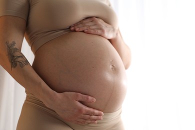 Photo of Pregnant woman near window at home, closeup. Space for text