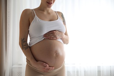 Photo of Pregnant woman near window at home, closeup. Space for text