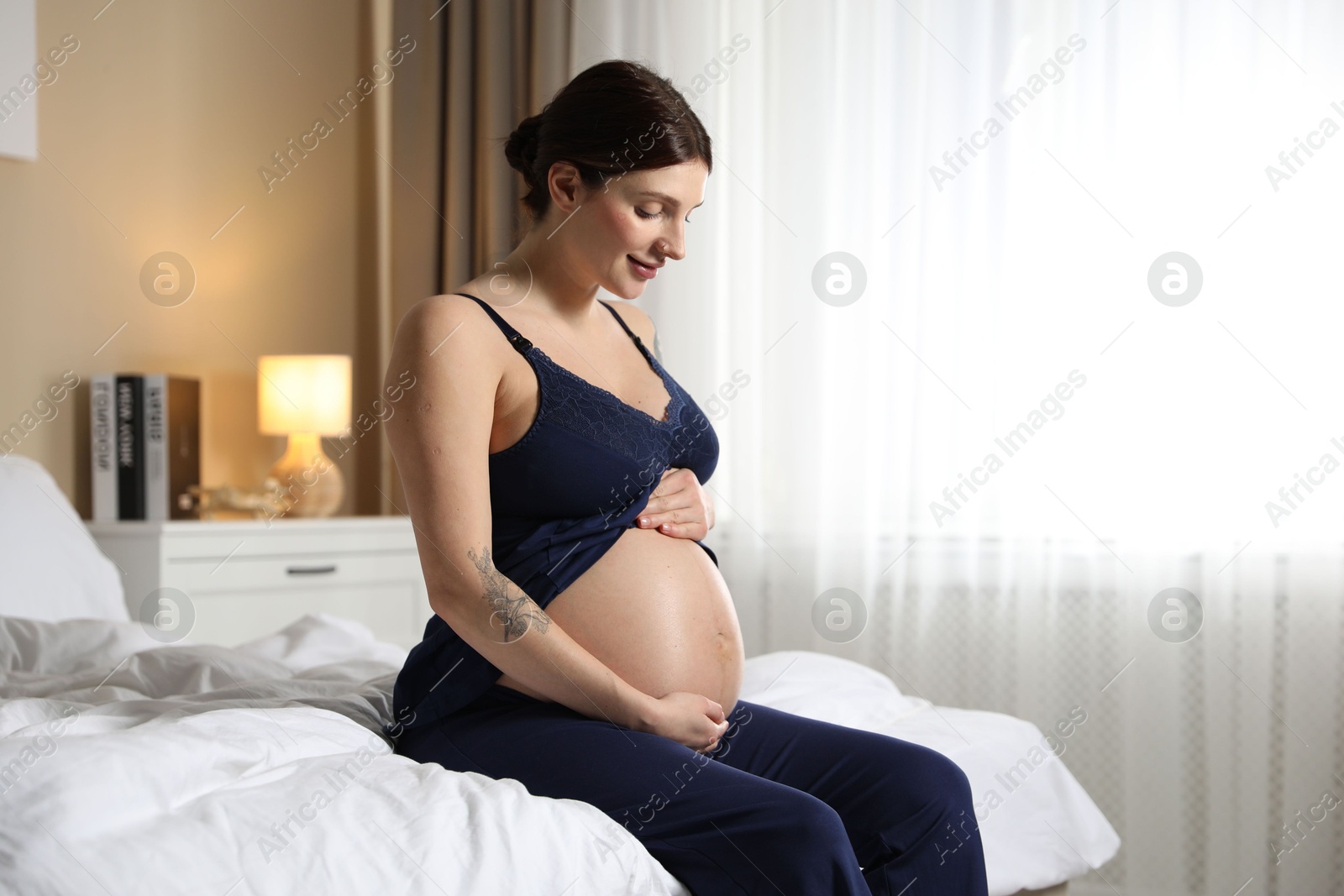 Photo of Beautiful pregnant woman on bed at home. Space for text