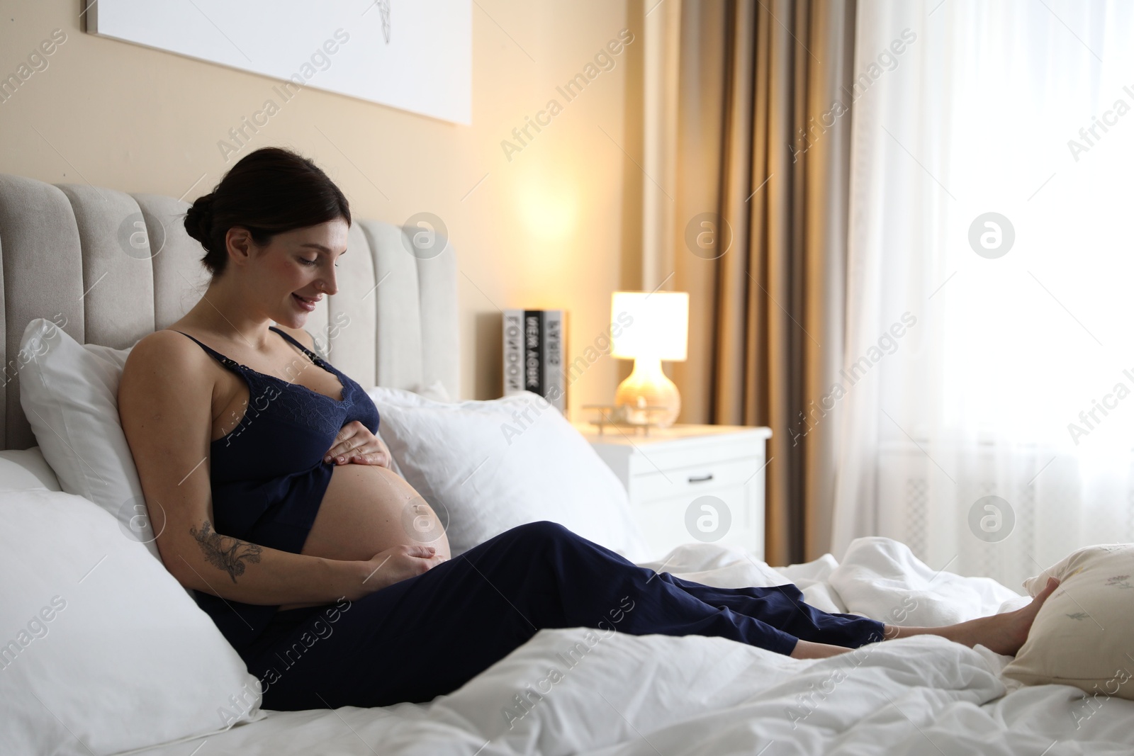 Photo of Beautiful pregnant woman on bed at home. Space for text