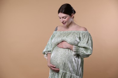 Photo of Beautiful pregnant woman with cute belly on beige background