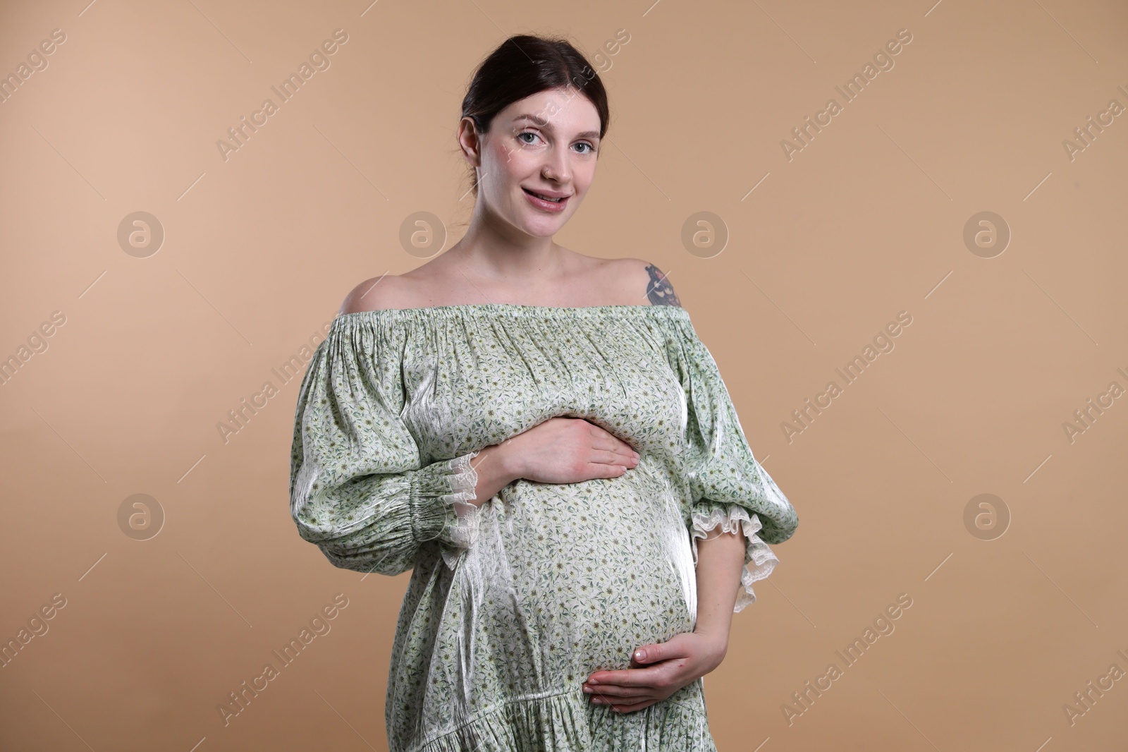 Photo of Beautiful pregnant woman with cute belly on beige background