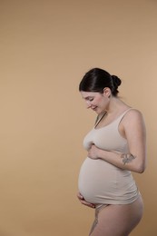 Photo of Beautiful pregnant woman with cute belly on beige background