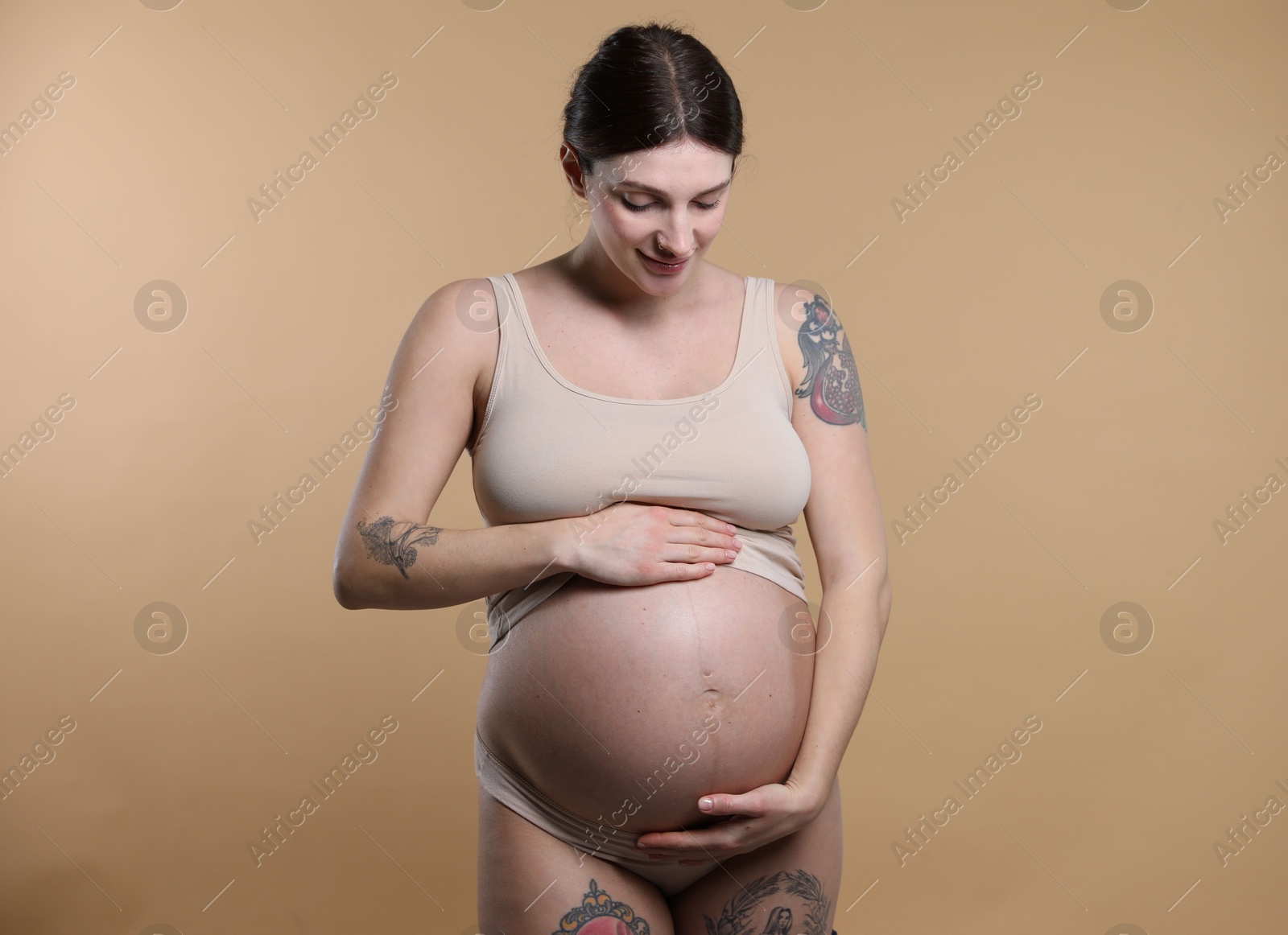 Photo of Beautiful pregnant woman with cute belly on beige background