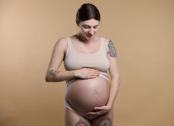 Photo of Beautiful pregnant woman with cute belly on beige background