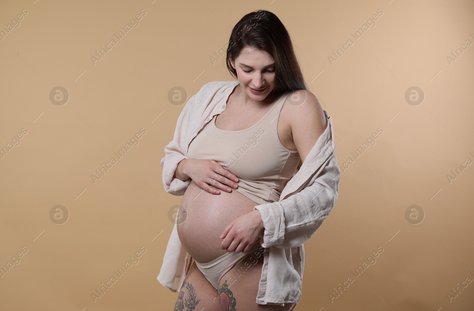 Photo of Beautiful pregnant woman with cute belly on beige background