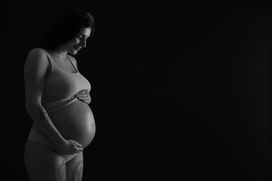 Photo of Beautiful pregnant woman with cute belly on dark background, space for text. Black and white effect