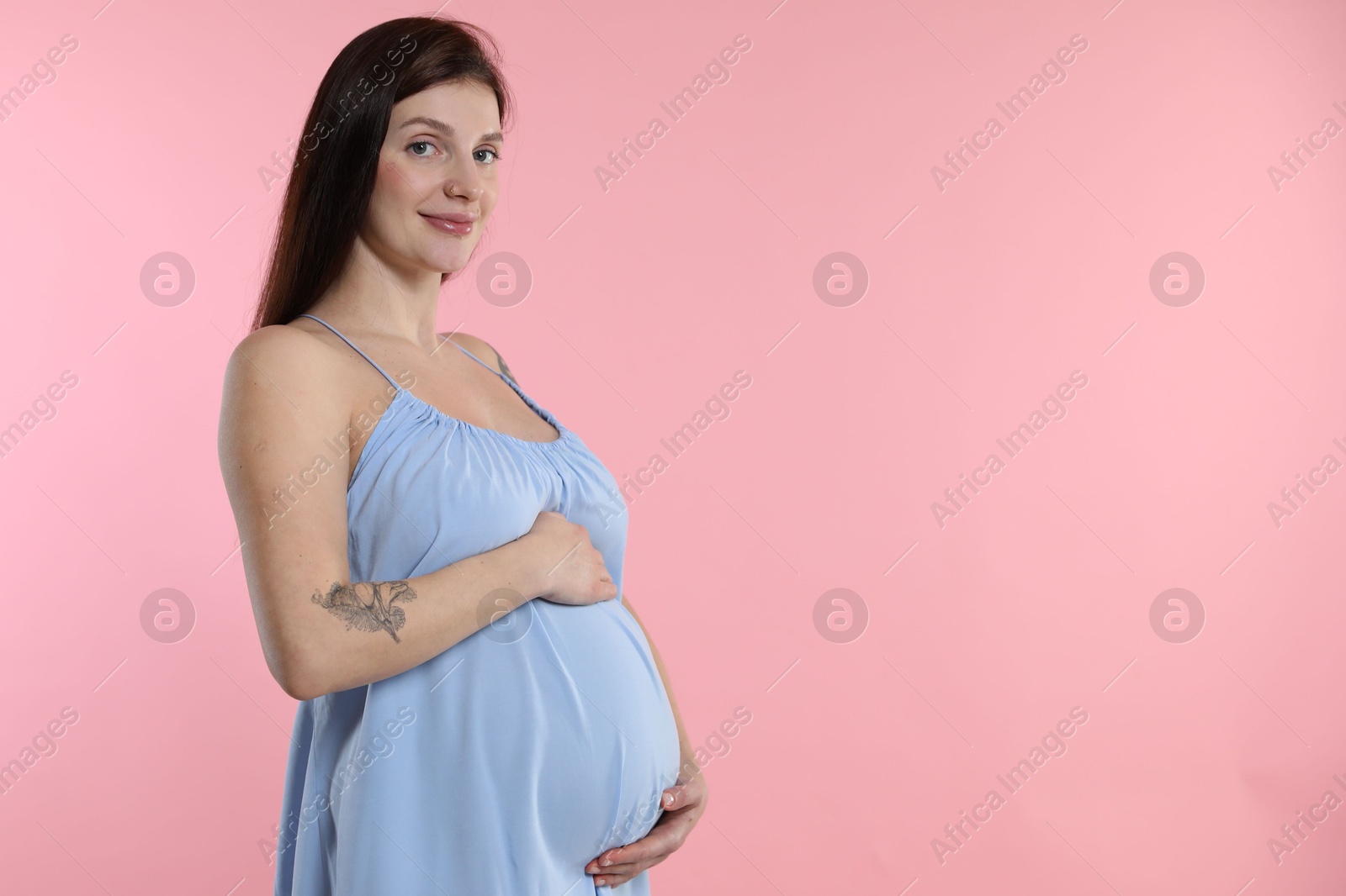 Photo of Beautiful pregnant woman with cute belly on pink background. Space for text