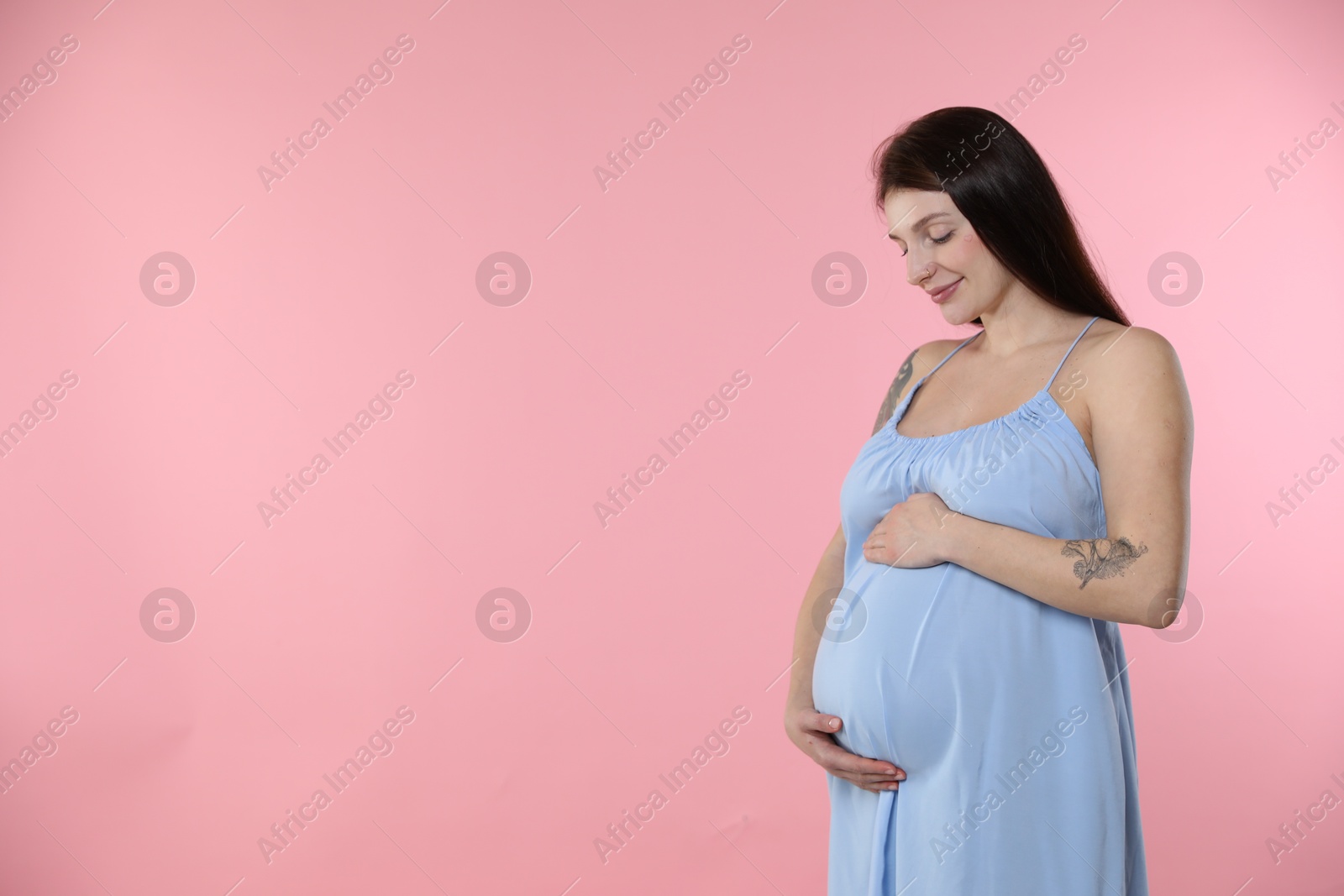 Photo of Beautiful pregnant woman with cute belly on pink background. Space for text