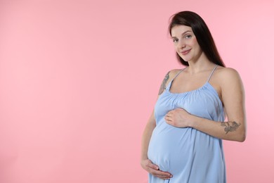 Photo of Beautiful pregnant woman with cute belly on pink background. Space for text