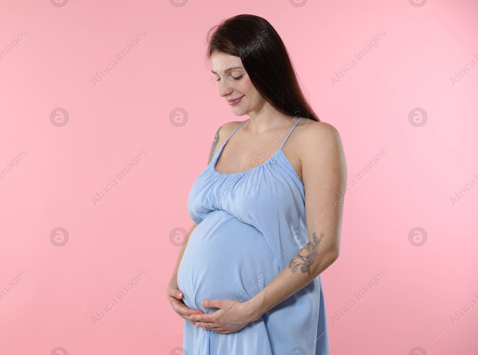 Photo of Beautiful pregnant woman with cute belly on pink background