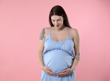 Photo of Beautiful pregnant woman with cute belly on pink background