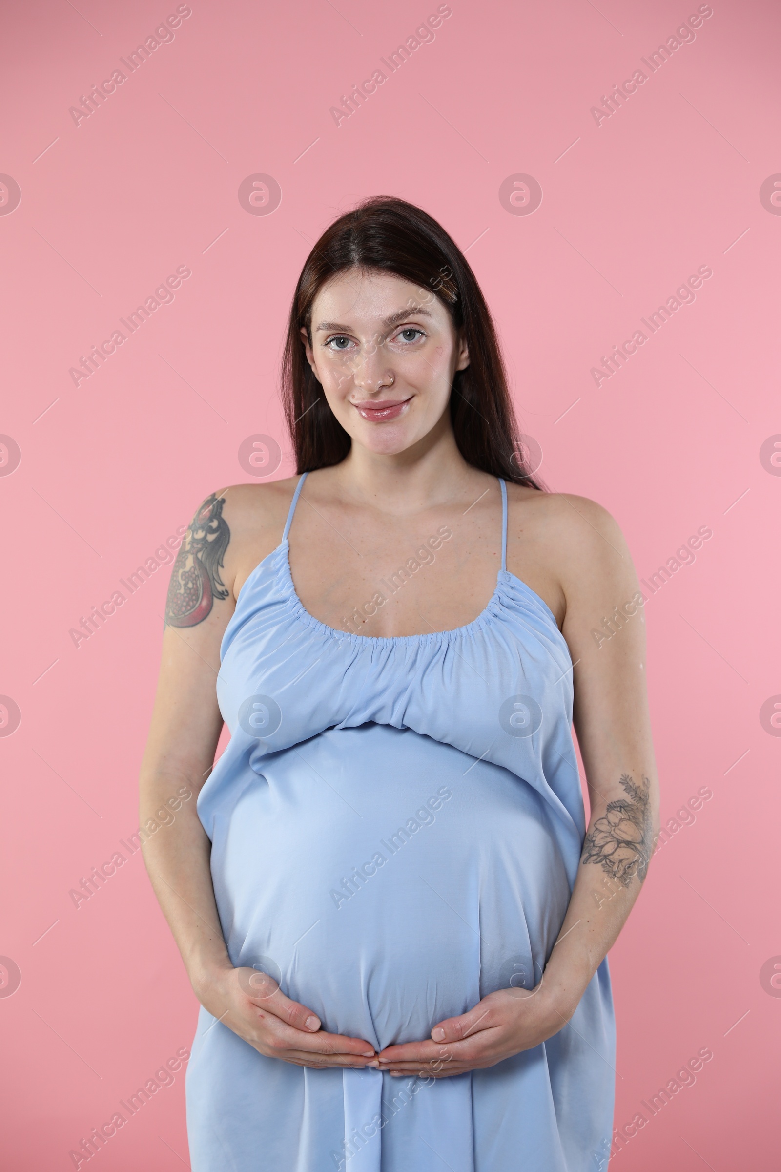 Photo of Beautiful pregnant woman with cute belly on pink background