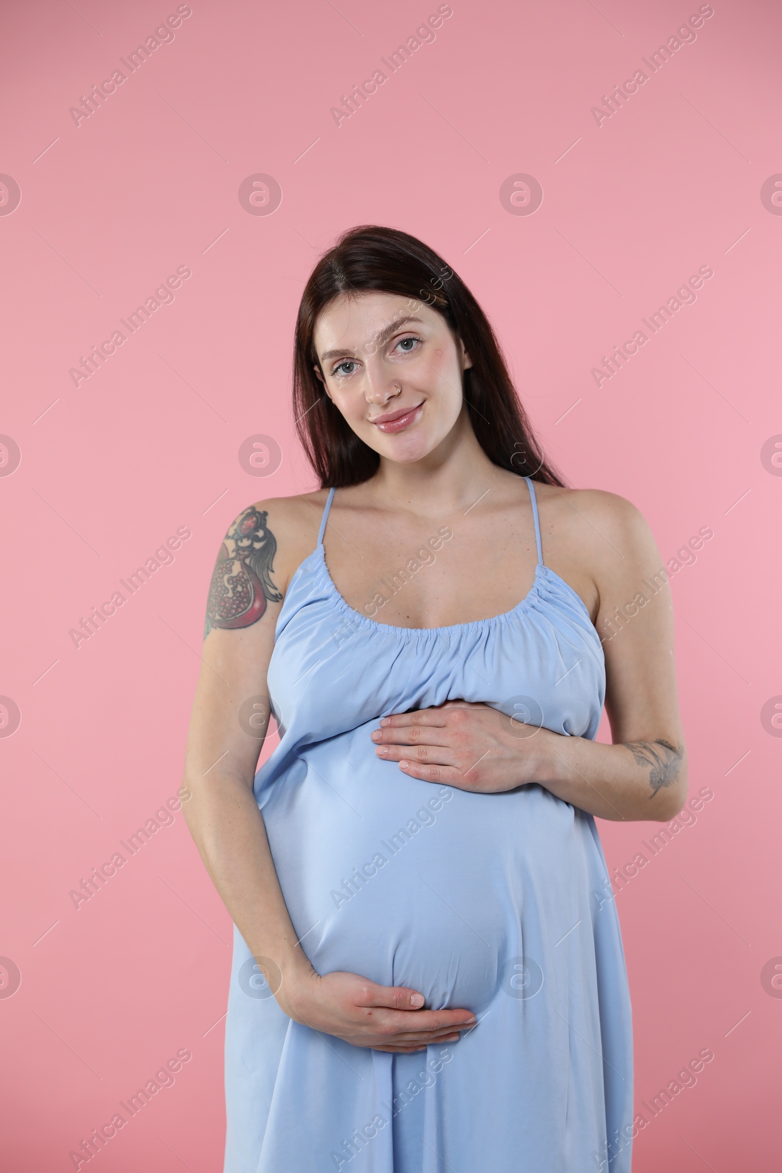 Photo of Beautiful pregnant woman with cute belly on pink background